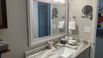 A bathroom with a large mirror, a sink, and two towel rings.