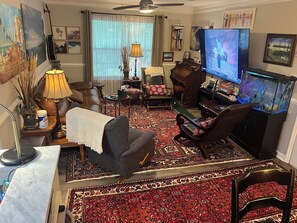 A living room with a sofa, armchairs, a television, a piano, and a fish tank. - Secluded 3 bed 2 bath condo close to Memorial Park, Five-points, & UGA in Athens (Athens)