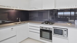 A modern kitchen with a gas stove, oven, and microwave. There are cabinets and a countertop. - 1 Bedroom + Study SPA on High Floor — Q Stay (Surfers Paradise)