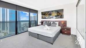 Ein modernes Schlafzimmer mit einem großen Bett, einem Nachttisch, Blick auf die Stadt durch raumhohe Fenster und einem Stadtpanorama-Gemälde an der Wand.