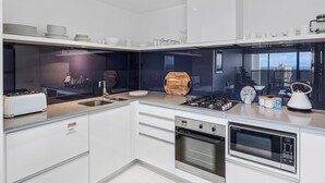 Une cuisine moderne équipée d’un four encastré, d’un four à micro-ondes et d’une cuisinière à gaz.