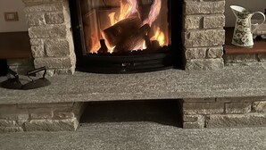 A stone fireplace with a fire burning inside, surrounded by stone walls and a mantelpiece with decorative items. - Casa San Rocco Piemonte - bjergtop - 360 udsigt - pool. (Montabone)