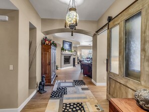 Un corridoio con un armadietto in legno, un tappeto decorato e una lampada a soffitto ornamentale.