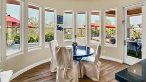 A sunlit room with a round table and chairs, large windows, and a view of an outdoor patio area. - Oasis in the desert - your hiking and biking paradise. (Scottsdale)