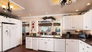 A modern kitchen with white cabinetry, a central island, and a built-in oven. - Big Bear Biltmore. Walk to the Park and Lake. Spa. (Big Bear Lake)