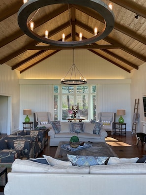 A spacious living room with a high ceiling, a large chandelier, and a view through large windows. - Newly renovated mountain view home in High Hampton, minutes from Cashiers, NC (Cashiers)