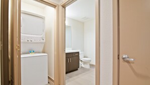A compact bathroom with a white toilet, a cabinet, and a washing machine.