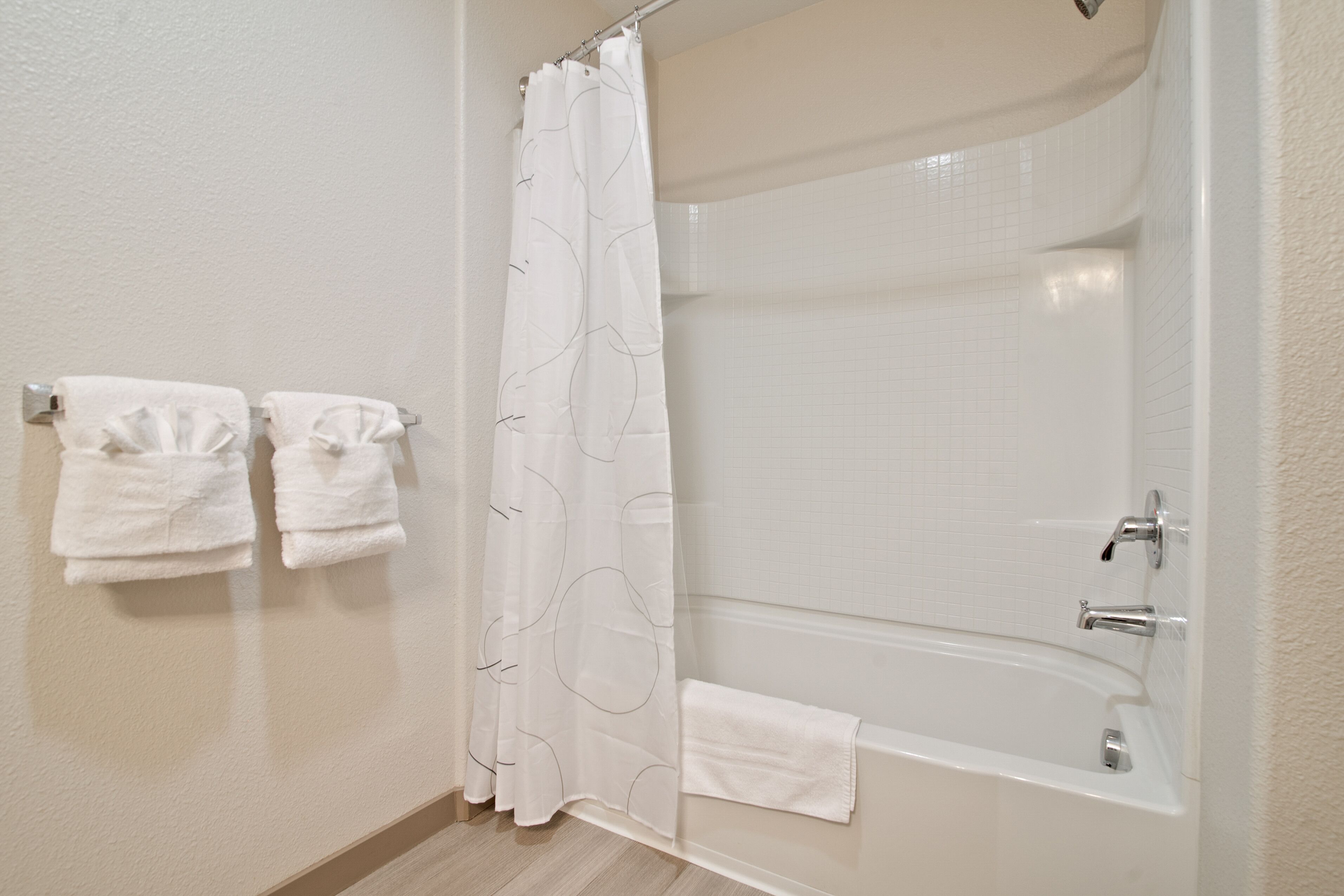 Une salle de bain équipée d’une douche, d’une baignoire et de deux serviettes accrochées au mur.