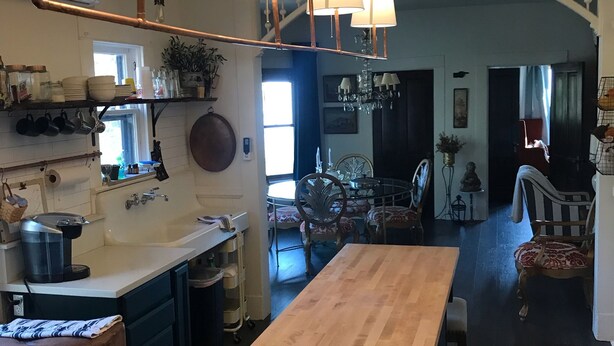 A spacious kitchen with a central island, pendant lighting, and a view into the dining area. - Historic Hoffman House (Auburn)