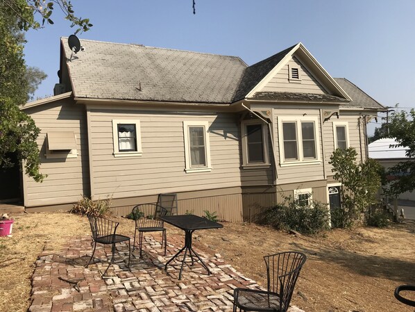 A house with a brick patio, a satellite dish, and a small garden area.