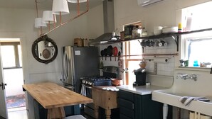 A compact kitchen with a wooden table, stools, a stove, and a sink. - Historic Hoffman House (Auburn)