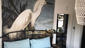 A bedroom with a bed, a mural of a bird, and a view of the outdoors. - Historic Hoffman House (Auburn)