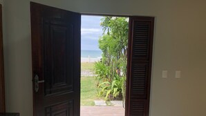 An open door leading to a view of the ocean and a garden.