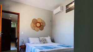 A bedroom with a bed, a wall-mounted air conditioner, and a ceiling light.