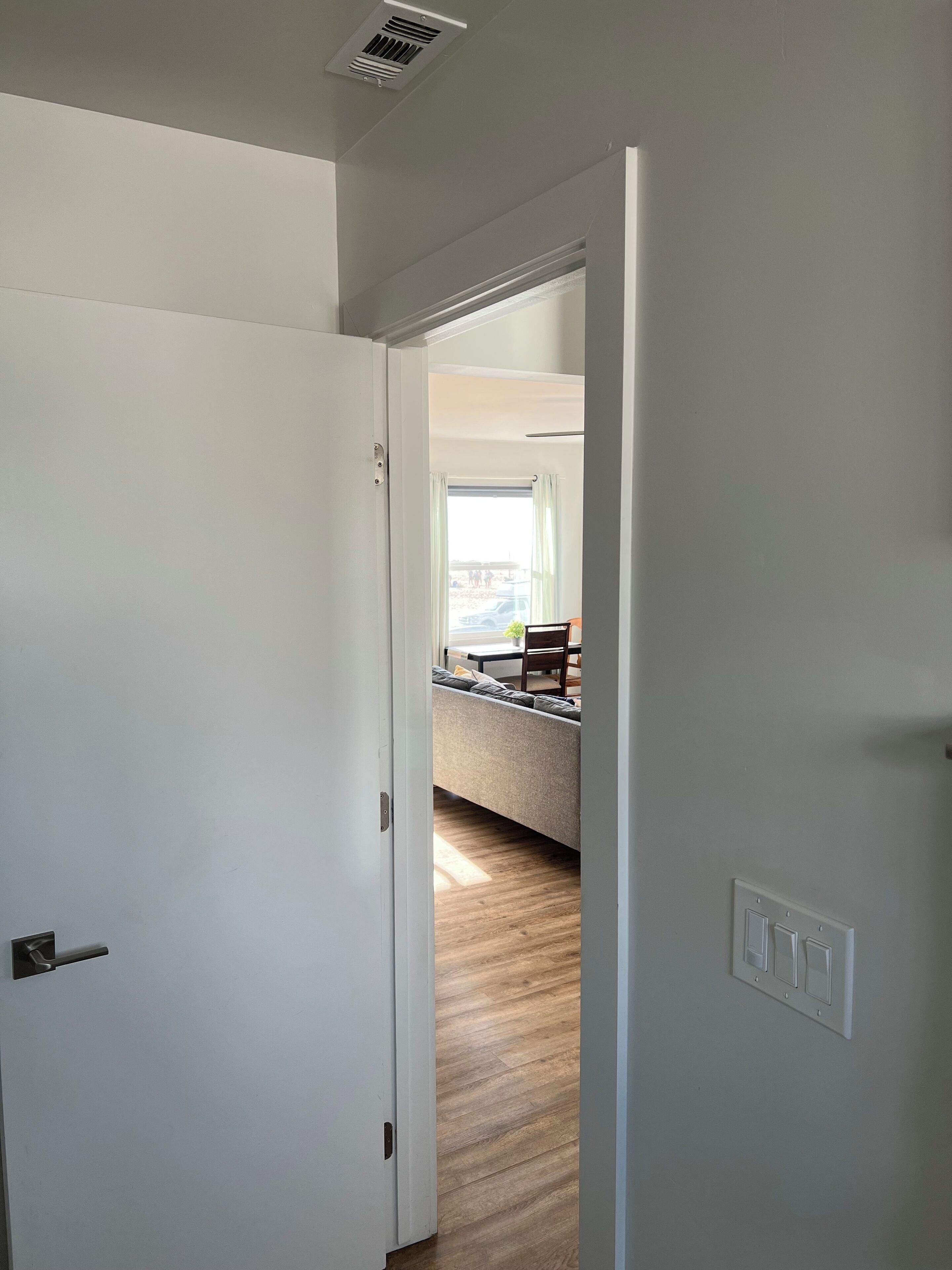 A hallway leading to a living area with a sofa and a dining table.