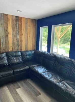 Relax in this cozy corner room with a comfortable leather sofa and large window.