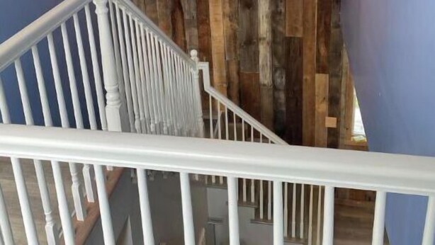 A staircase with a white railing leading to a room with a wooden wall panel and hanging pendant lights. - Barn and bling on Windrock (Oliver Springs)