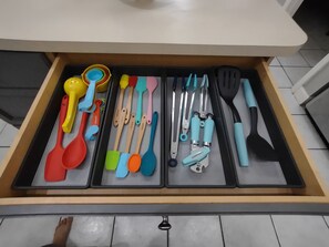 Un tiroir contenant divers ustensiles de cuisine, rangés par couleur.