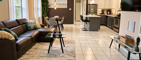 A modern living room with a sofa, coffee table, and dining area.