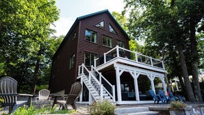 A wooden cabin with a balcony and stairs leading to a porch area. - Maple Cove Lodge on Lake Sebago Waterfront! (Casco)