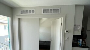 Ein modernes Wohnzimmer mit einer Couch, einer gestreiften Tagesdecke und Blick auf einen Balkon.