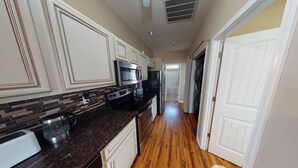 A kitchen with white cabinets, a microwave, stove, and a toaster. - Cute beach house, 2 min walk to the beach (Myrtle Beach)