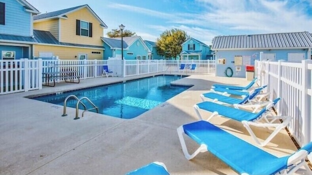 A swimming pool area with lounge chairs and a white fence. - Cute beach house, 2 min walk to the beach (Myrtle Beach)