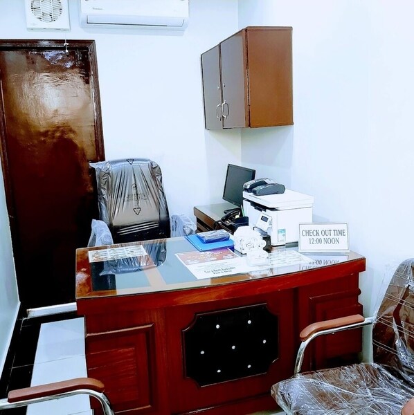 A reception desk with a sign indicating check-out time, a computer, a printer, and a telephone. - Galaxy Inn Guest House (Karachi)