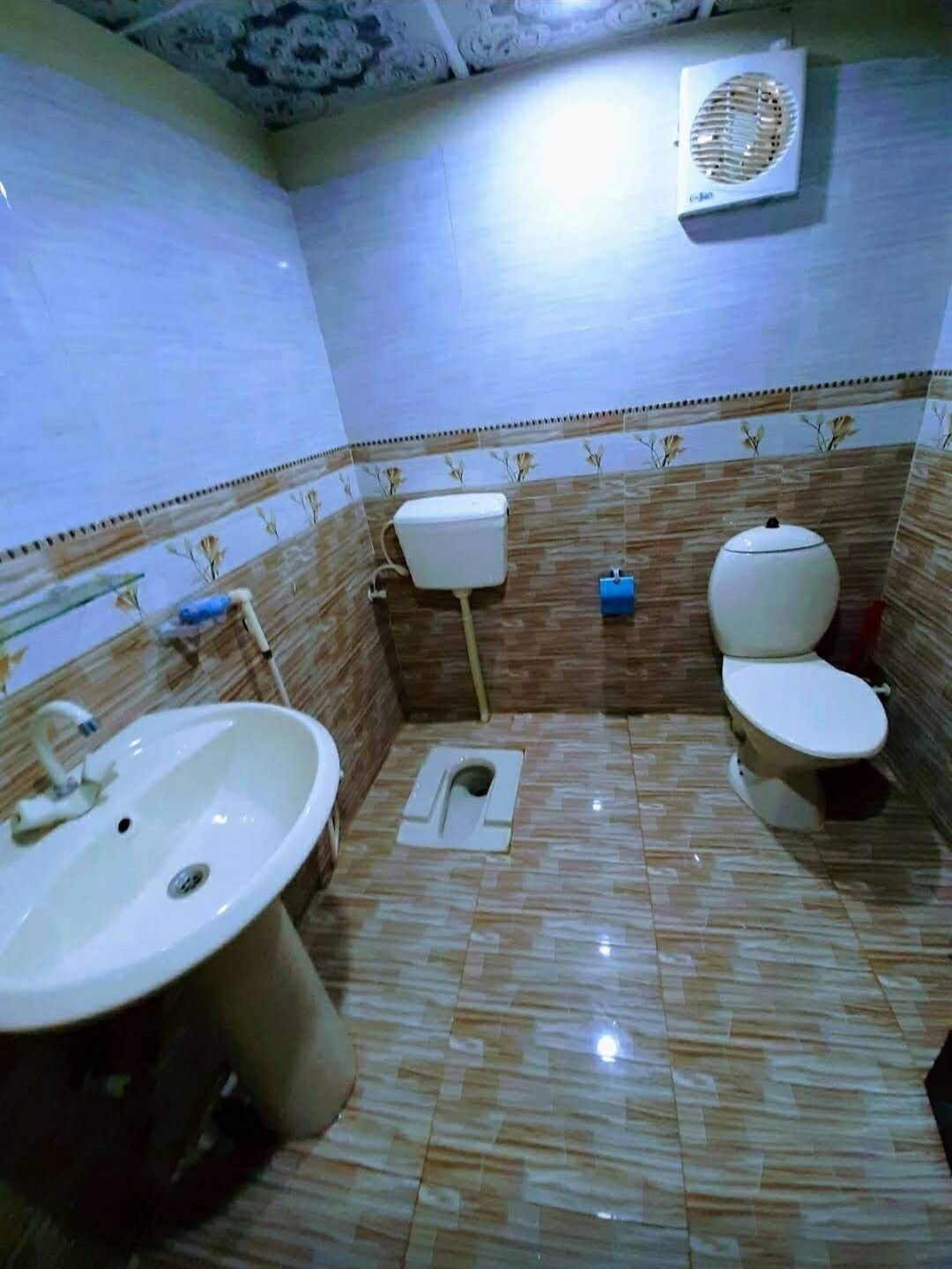 A bathroom with two toilets, a sink, and a toilet paper holder.