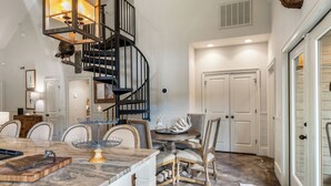 A spacious kitchen with a marble countertop, a wooden island, and a black spiral staircase. - Woodland Gameday Getaway Near Tuscaloosa – Pond Views, Pavilion, Firepits & More (Akron)