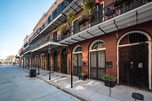 Una hilera de edificios históricos con ventanales arqueados y balcones, una acera y una calle.