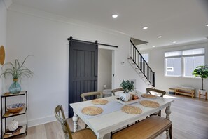 Un comedor con una mesa blanca, individuales tejidos y sillas de madera.