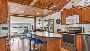 A kitchen with wooden cabinets, a stainless steel oven, and a large island with bar stools. - Lakefront Cottage with kayaks, paddleboat, aqua mat, & BIG deck close to Elkhart (Saint Cloud)