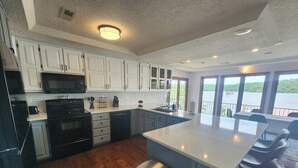Una cocina moderna con armarios blancos, una isla grande y vista a un lago.