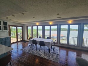 A spacious dining area with a view of a lake, wooden flooring, and a table set for four.