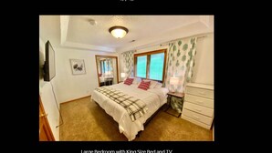 Un amplio dormitorio con una cama king size, televisión y cómoda.