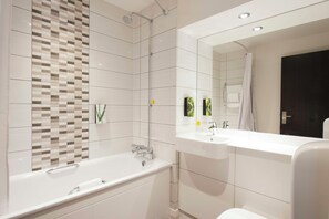 A modern bathroom with a freestanding bathtub, a double sink vanity, and a large mirror. - Premier Inn Portsmouth Havant South (Havant)