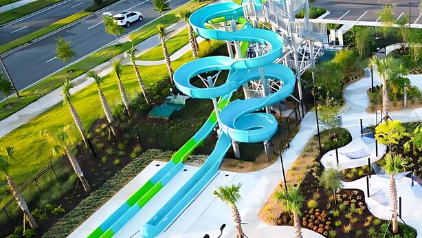 Vue aérienne d’un parc aquatique avec de nombreux toboggans et un espace de stationnement.