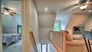 A spacious attic bedroom with a large bed, a ceiling fan, and a view of the outdoors. - 3 Mi to Beaches: Tranquil Cape Cod Escape w/ Deck (Bourne)