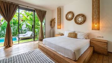 A bedroom with a large bed, wooden nightstands, a view of a pool, and tropical plants.