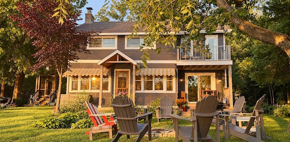 Une maison à deux étages avec un porche à l’avant, une terrasse couverte et un petit balcon.