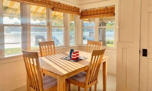 A dining area with a table and chairs, large windows with views of a lake, and a ceiling with a patterned design. - Cozy Crystal Lakefront Cottage (Plymouth)