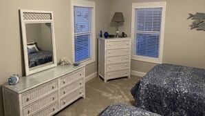 A bedroom with two beds, a dresser, and a mirror. - Promise Land Gem (Morehead City)