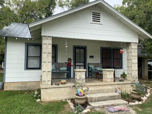 A house with a porch, a small garden, and a welcome mat.