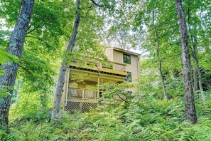 Escape to a secluded cabin surrounded by lush forest and enjoy a tranquil view from the upper balcony.