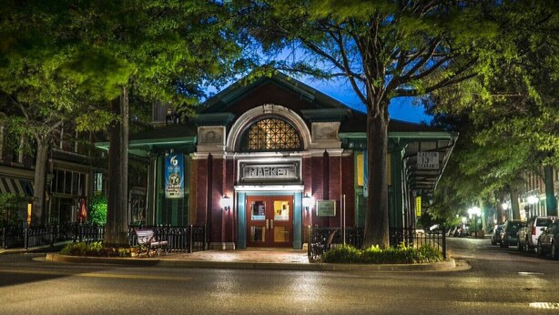 A building with a marquee sign, a gated entrance, and a street with parked cars. - The Dim Light Lower Town Luxury Boutique Condos (Paducah)