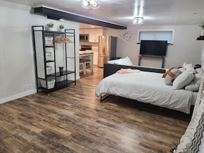 A bedroom with a bed, a desk, and a kitchenette. - Haney Hideaway (Colorado Springs)