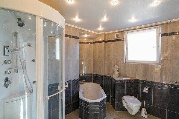 Une salle de bain dotée d’une douche à parois de verre, d’une baignoire sur pieds, de toilettes et d’un meuble-lavabo avec un miroir.