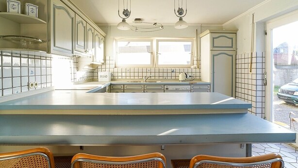 A kitchen with a large island, two hanging pendant lights, and a window with a view of the street. - ARTHUR Historic vacation home Moselle (Mülheim (Mosel))