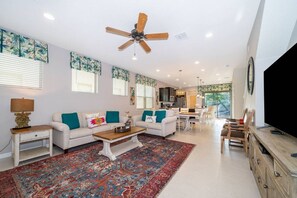 Un salon spacieux doté d’un ventilateur de plafond, d’un grand tapis et d’un téléviseur.